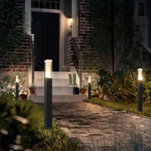 Load image into Gallery viewer, Veracruz outdoor wall light illuminated at dusk, warm white glow on garden path
